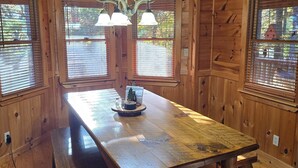 A wooden interior with a central dining table, benches, and a chandelier. - Blue Ridge, North GA Cabin: Sleeps 10 & 2 pets • hot tub • Fast wifi • fire pit (Blue Ridge)