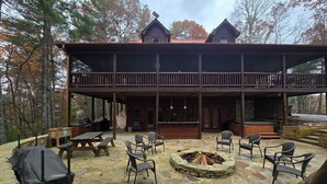 A wooden cabin with a stone patio, outdoor seating, and a fire pit. - Blue Ridge, North GA Cabin: Sleeps 10 & 2 pets • hot tub • Fast wifi • fire pit (Blue Ridge)