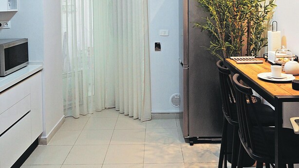 A compact kitchen with a refrigerator, microwave, and dining table with chairs.