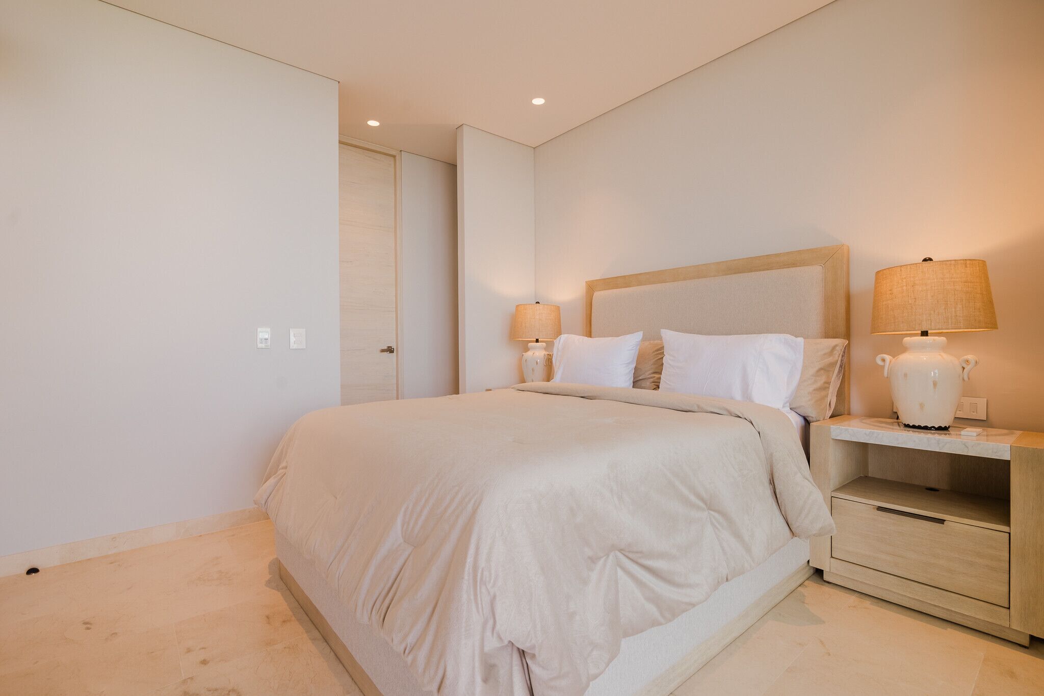 Une chambre moderne avec un grand lit, des tables de chevet avec des lampes et une armoire.