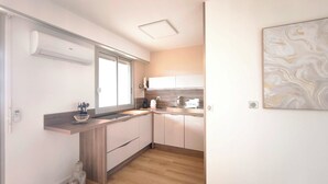 Una cocina moderna con encimera de madera, armarios blancos y una ventana.