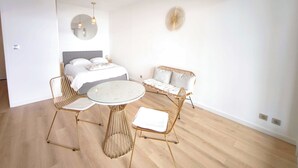 Un dormitorio moderno con una cama, una mesita de noche y una mesa redonda de cristal con sillas.