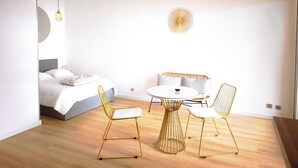 Un dormitorio moderno con cama, mesita de noche y una mesa redonda de comedor con sillas.