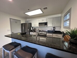 A modern kitchen with a central island, stainless steel appliances, and bar stools. - Modern Resort Home @ Starr Pass Golf Resort (Tucson)