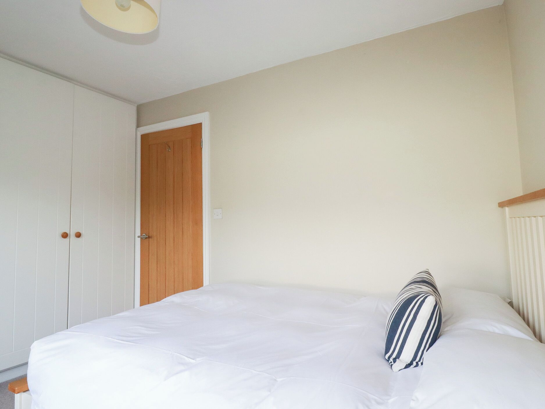 A bedroom with a large bed, a wooden door, and a white wardrobe.