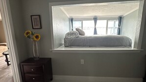 A bedroom with a skylight, a bedside table with a vase of sunflowers, and a window with curtains. - Manatee Riverfront Home , Cozy 2-bedroom house in Ellenton “Duplex”, left side.  (Ellenton)