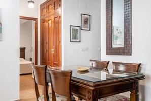 Uma área de jantar com mesa de vidro, cadeiras de madeira e um armário de madeira.