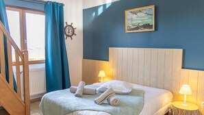 Un dormitorio con una cama, dos lámparas de noche, una rueda de barco y un cuadro en la pared.