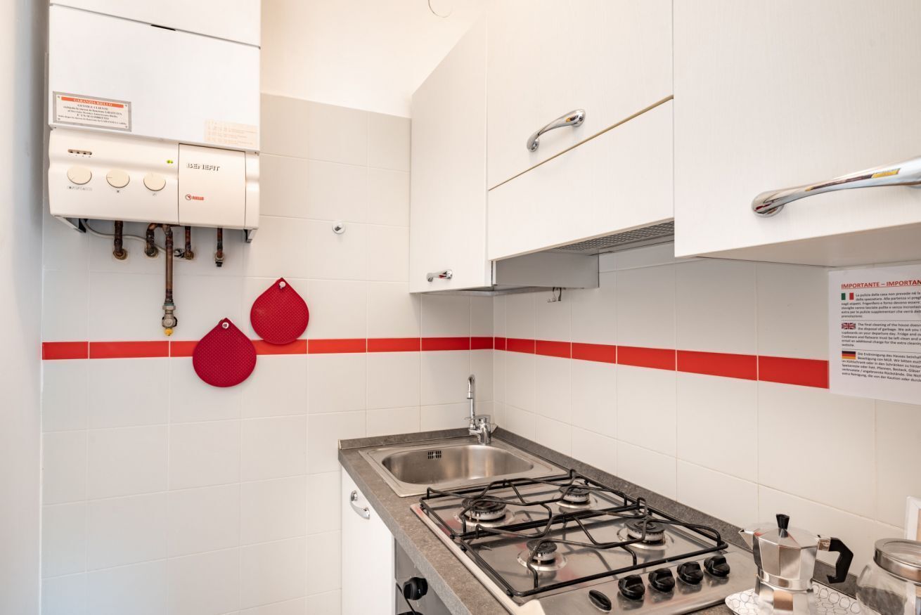 Een keuken met een gasfornuis, een spoelbak en een wandwaterverwarmer.