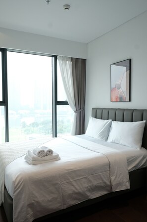 A modern hotel room with a large bed, a city view, and a framed artwork on the wall. - Metropole The Crest Thu Thiem Apartment (Thu Duc)