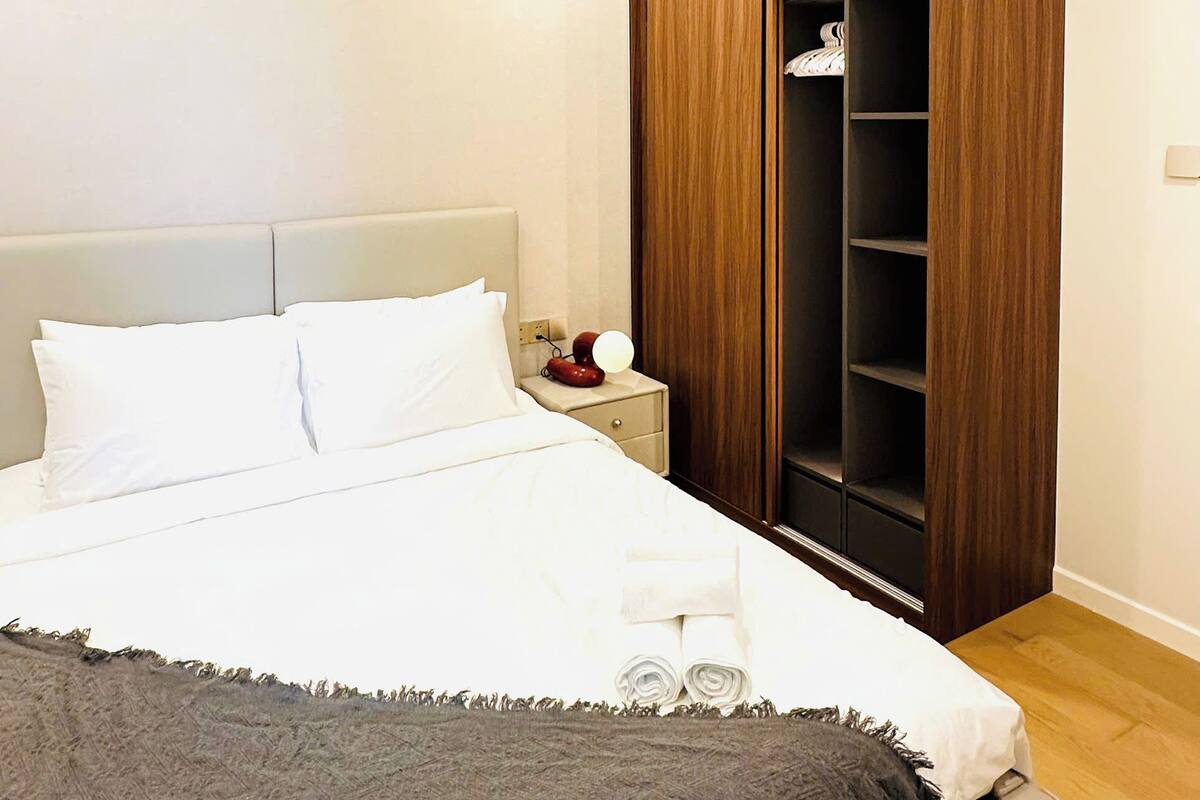 A bedroom with a bed, a nightstand, and a wooden wardrobe.