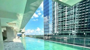 A modern indoor pool with clear water, surrounded by high-rise buildings and a large overhang structure. - Metropole The Crest Thu Thiem Apartment (Ho Chi Minh City)