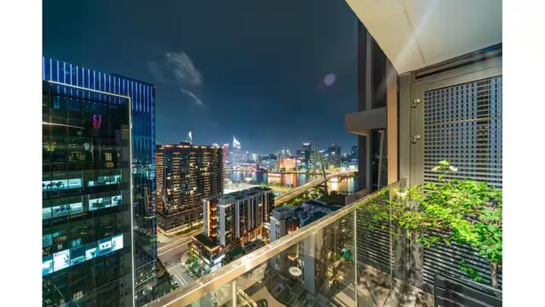 A nighttime cityscape with modern buildings, a river, and a bridge. - Metropole The Crest Thu Thiem Apartment (Ho Chi Minh City)