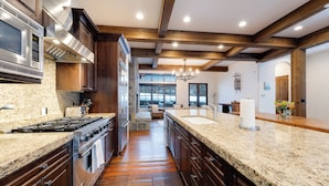 A spacious kitchen with granite countertops, stainless steel appliances, and wooden beams. - Luxury at Whitefish Mountain chalet w/ hot tub (Whitefish)