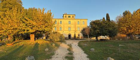 A large, yellow building with a gravel path leading to the entrance.