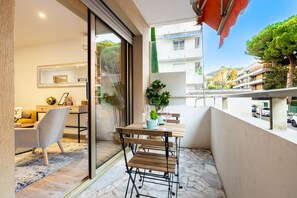 Un balcone con tavolo e sedie, una pianta in vaso e vista su edifici e alberi.
