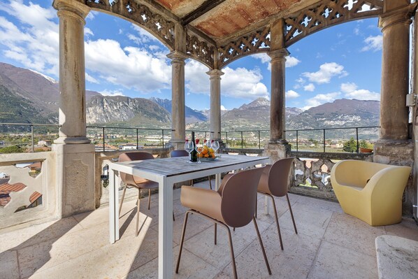 A terrace with a table, chairs, and a view of mountains.