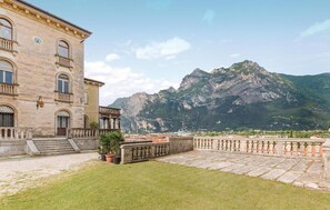 A building with a stone facade, a balcony, and a mountain backdrop.