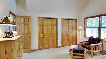 A spacious room with a large closet, a desk with a lamp, a chair, and a window with blinds.