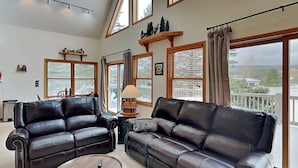 A spacious living room with two leather sofas, a round coffee table, and large windows offering a view of the outdoors. - Almost Heaven (Swanton)
