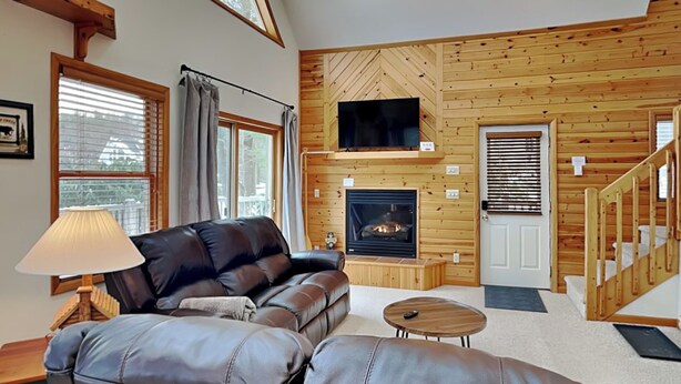A cozy living room with a leather sofa, a small coffee table, a fireplace, and wooden walls. - Almost Heaven (Swanton)