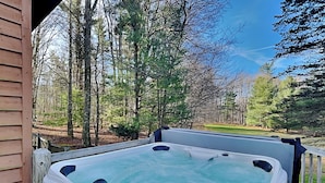 A hot tub on a wooden deck with a view of a forest and a golf course. - Almost Heaven (Swanton)