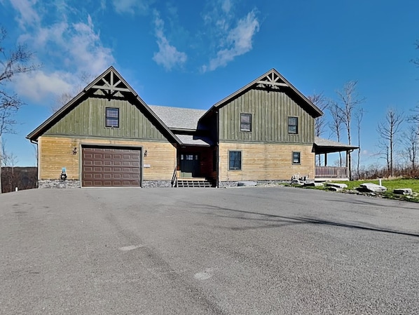 Een houten huis met twee verdiepingen, een garage, een overdekte veranda en een stenen fundering.