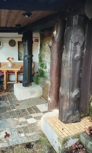 Ein rustikaler Außenbereich mit Steintreppen, die zu einer hölzernen Bank und einem Tisch mit Blumen in einer Vase führen.