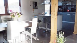 A modern living room with a sofa, dining area, and kitchen. - Vacation apartment in the Franconian Forest (Nordhalben)