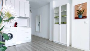 A modern kitchen with white cabinets, a built-in washing machine, and a potted plant. - Skyline Tower (Torre del Mar)