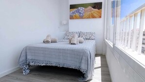 A bedroom with a bed, pillows, and a painting on the wall. - Skyline Tower (Torre del Mar)