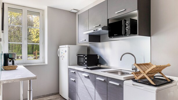 A modern kitchen with a built-in microwave, a coffee maker, and a dish rack.