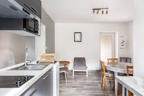 A modern kitchen with a built-in microwave, a stainless steel sink, and a dining area with a table and chairs.
