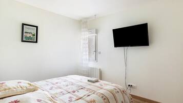 Une chambre à coucher avec un lit, un téléviseur, un radiateur et un tableau encadré au mur.