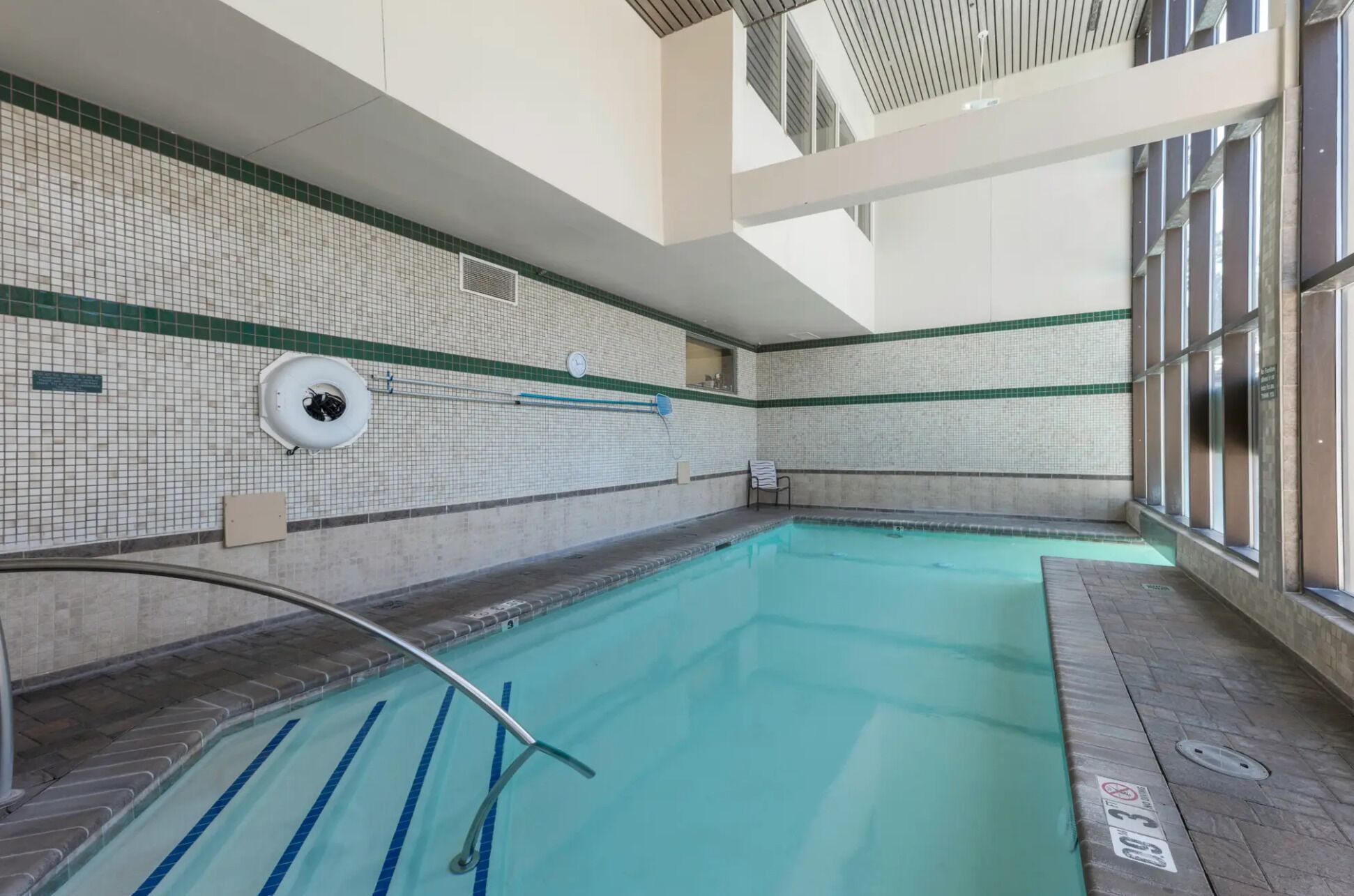 Ein Innenpool mit klarem, blauem Wasser, gefliesten Wänden und einer Decke mit Oberlichtern.
