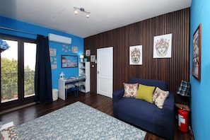Ein Wohnzimmer mit einem blauen Sofa, einem gemusterten Teppich und einer Holzwand mit Kunstwerken.