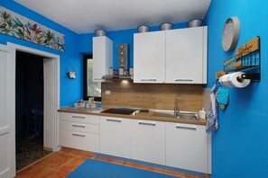 Eine Küche mit weißen Schränken, einer blauen Spritzschutzwand und einer Holzarbeitsplatte.