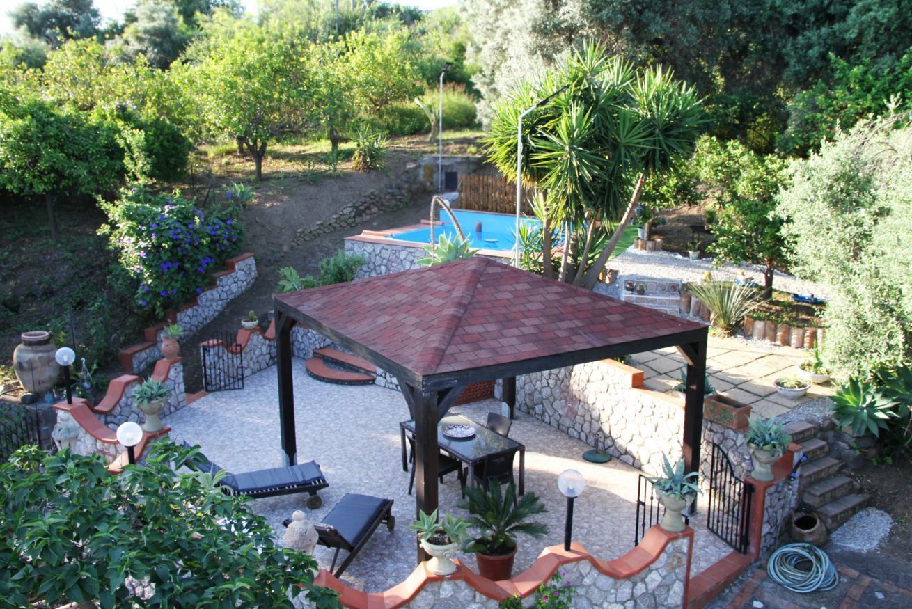 A covered patio area with a pool, stone walls, and outdoor seating.