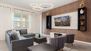 Ein modernes Wohnzimmer mit einem grauen Sofa, einem Couchtisch und einem an der Wand befestigten Fernseher.