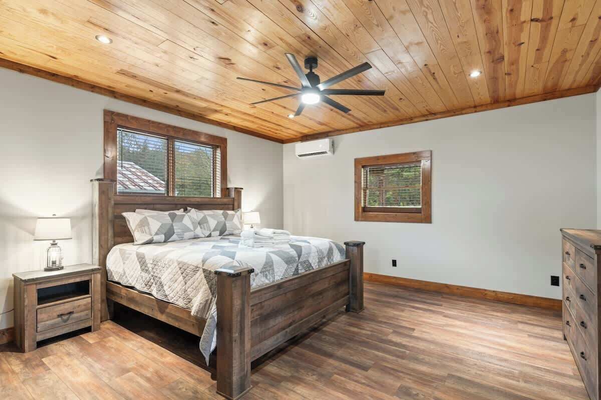 Ein Schlafzimmer mit Holzboden, einem Bett mit gemustertem Bettbezug, zwei Nachttischen und einer Kommode.