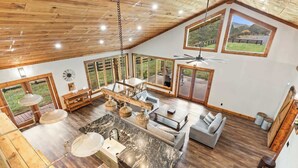 A spacious kitchen with a marble countertop and a dining area with a high ceiling and large windows.