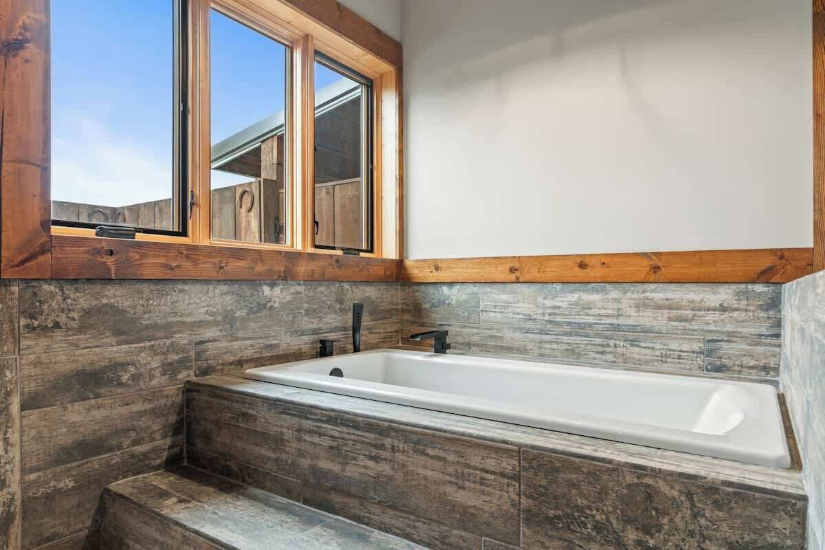 Une salle de bain avec un meuble-lavabo en bois, une baignoire et une fenêtre avec un cadre en bois.
