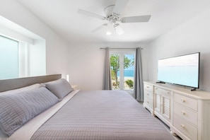 Ein Schlafzimmer mit Bett, Fernseher, Deckenventilator und Blick auf den Strand.