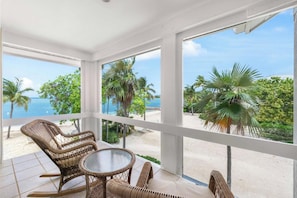 Ein Balkon mit Korbmöbeln mit Blick auf Strand und Palmen.