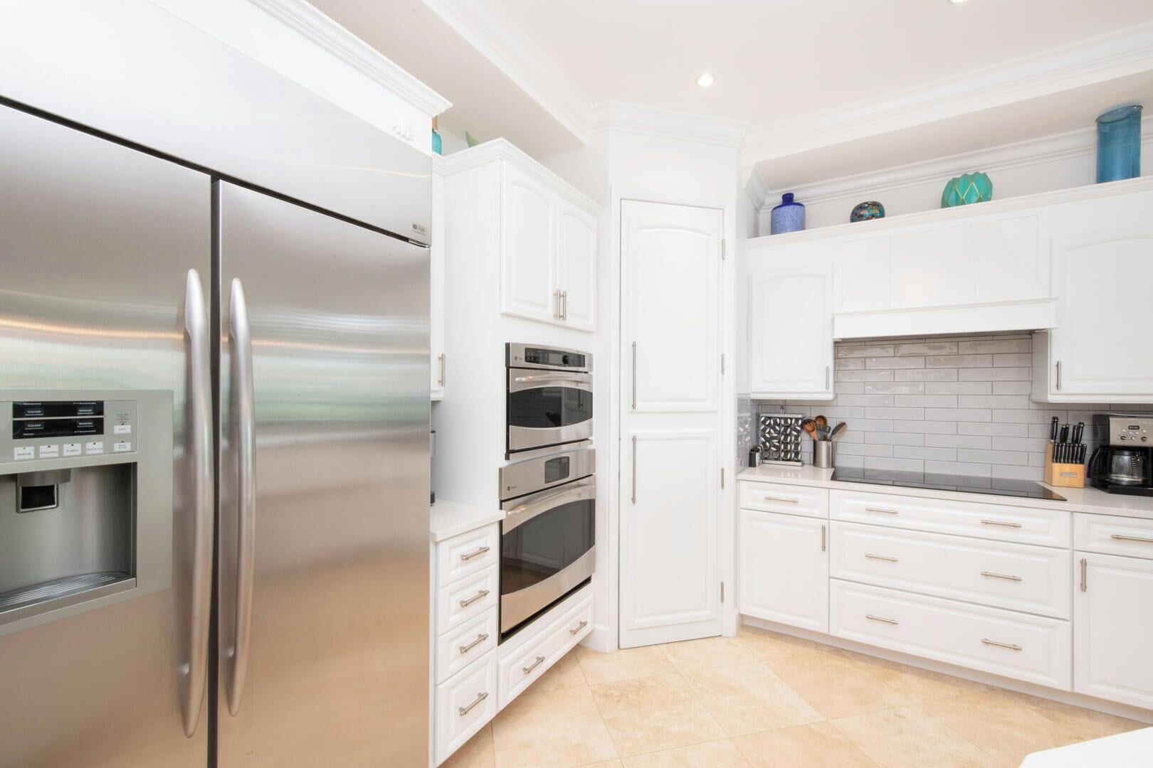 Una cocina moderna con electrodomésticos de acero inoxidable, armarios blancos y un salpicadero de azulejos.