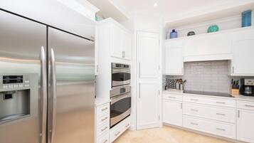 Una cocina moderna con electrodomésticos de acero inoxidable, armarios blancos y un salpicadero de azulejos.