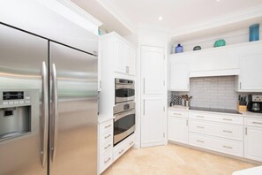A modern kitchen with stainless steel appliances, white cabinetry, and a tiled backsplash. - SeaBreeze 3 on 7 Mile Beach (Seven Mile Beach)