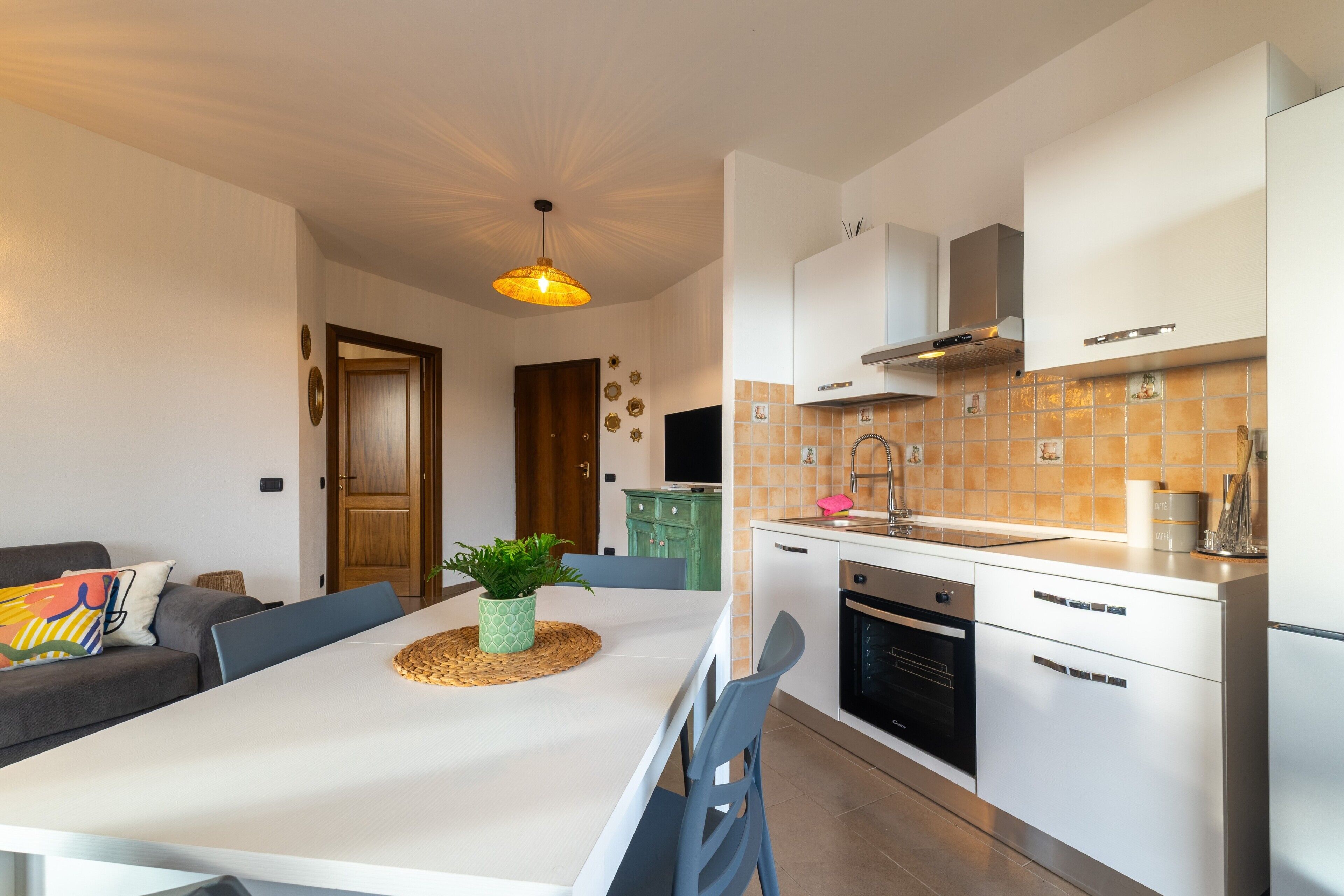 Een moderne keuken met witte kasten, een eettafel en een hangende吊灯