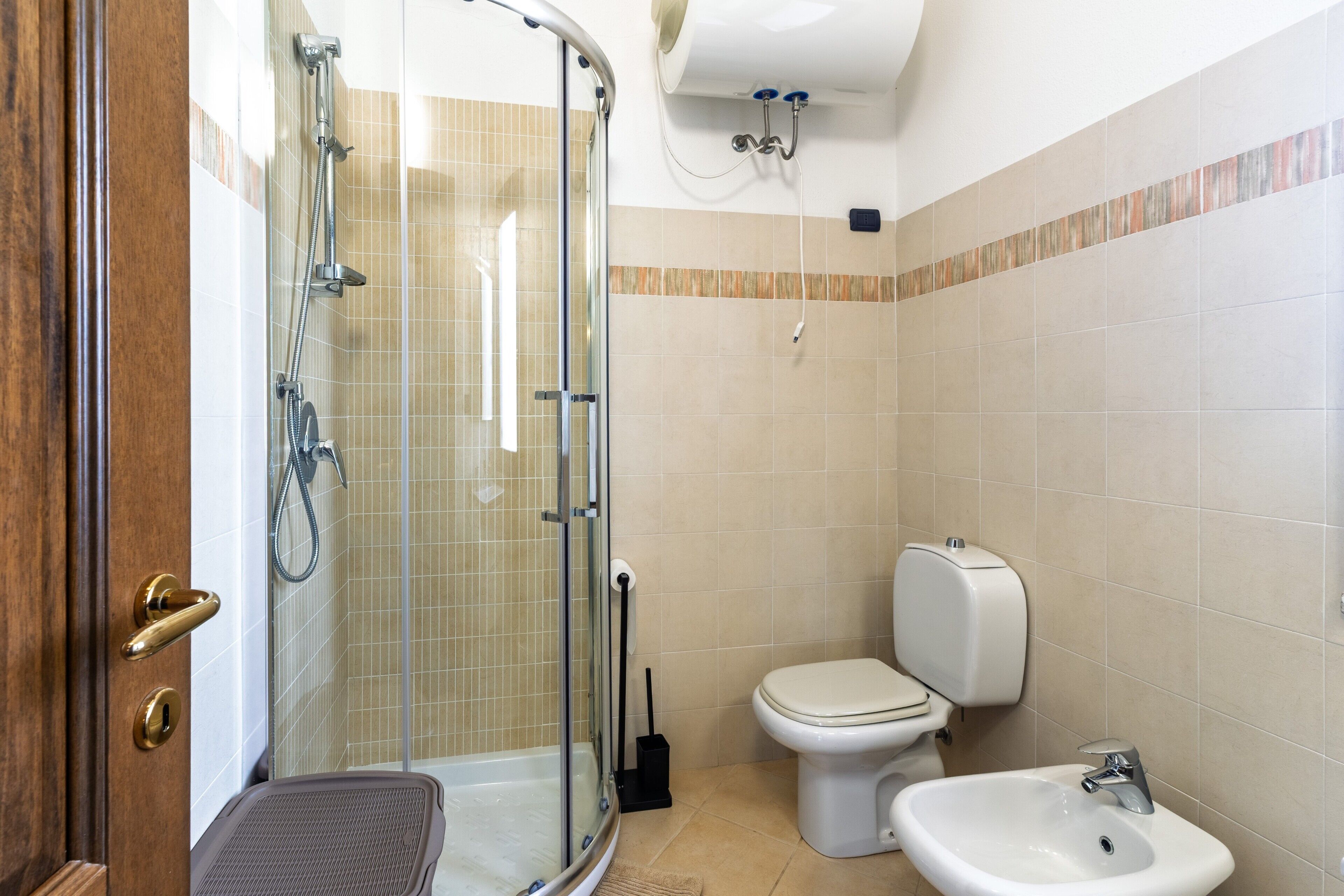 A bathroom with a glass shower enclosure, a toilet, and a sink.