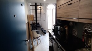 Una cucina moderna con piani di lavoro neri, mobili in legno e una sedia bianca.
